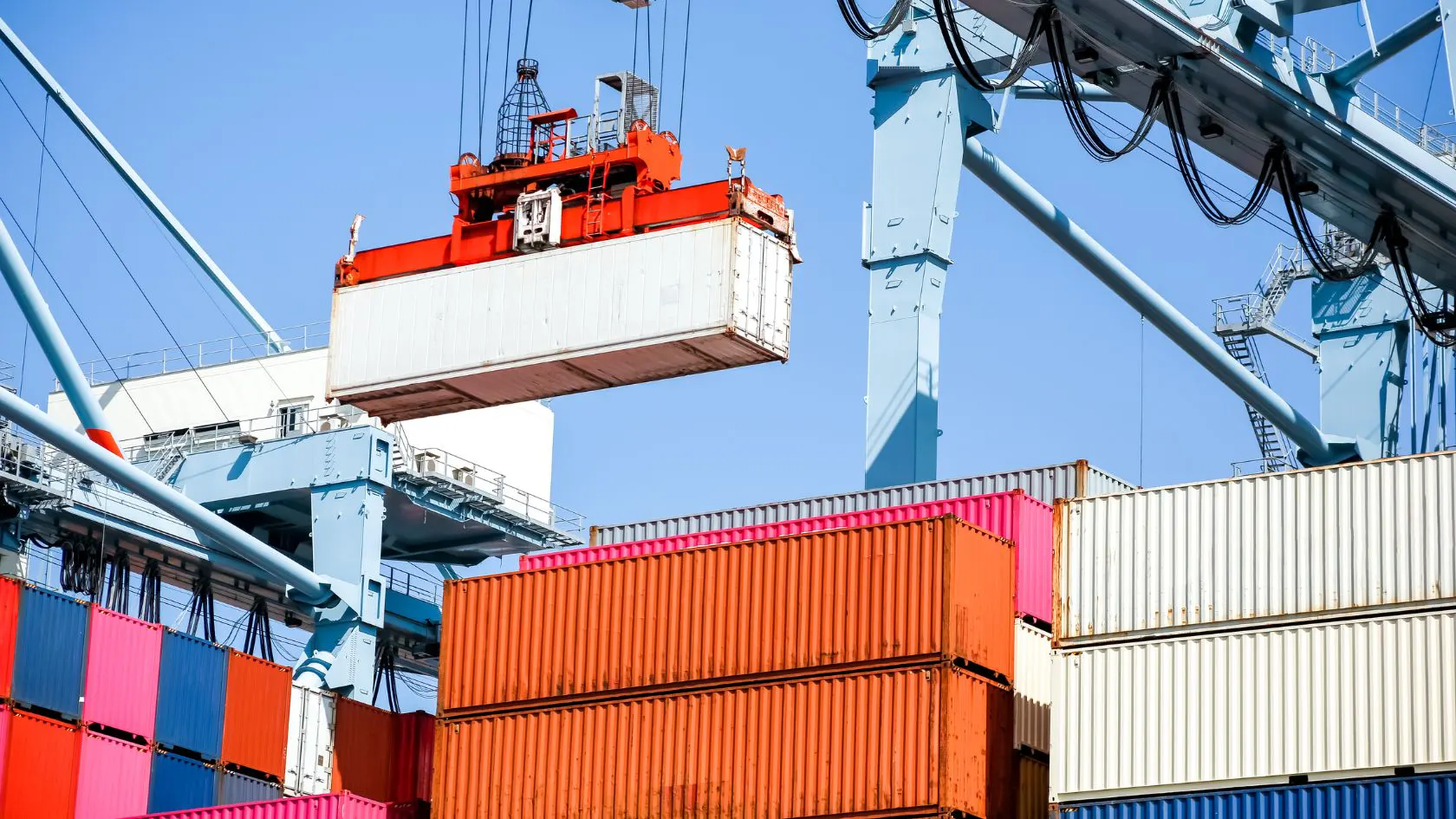 Shipping containers being loaded at a port with a crane